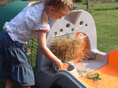 Image of the hay rack and water bottle being placed in the Eglu