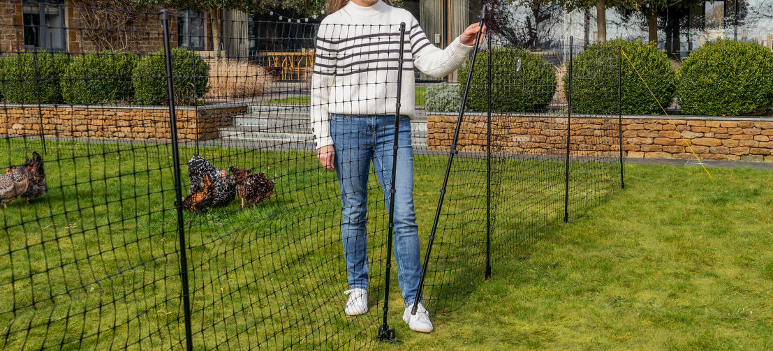 Woman opening the gate to her Omlet Chicken Fencing.