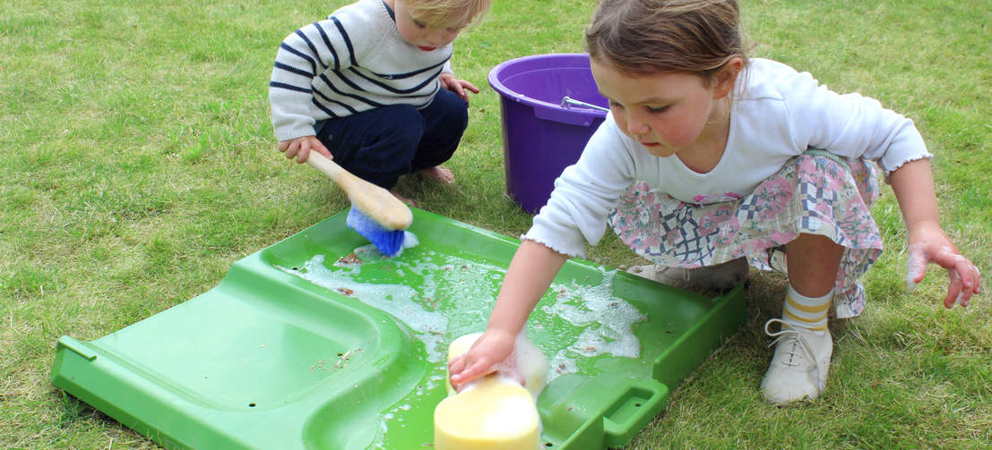 Two children cleaning the Eglu dropping tray.
