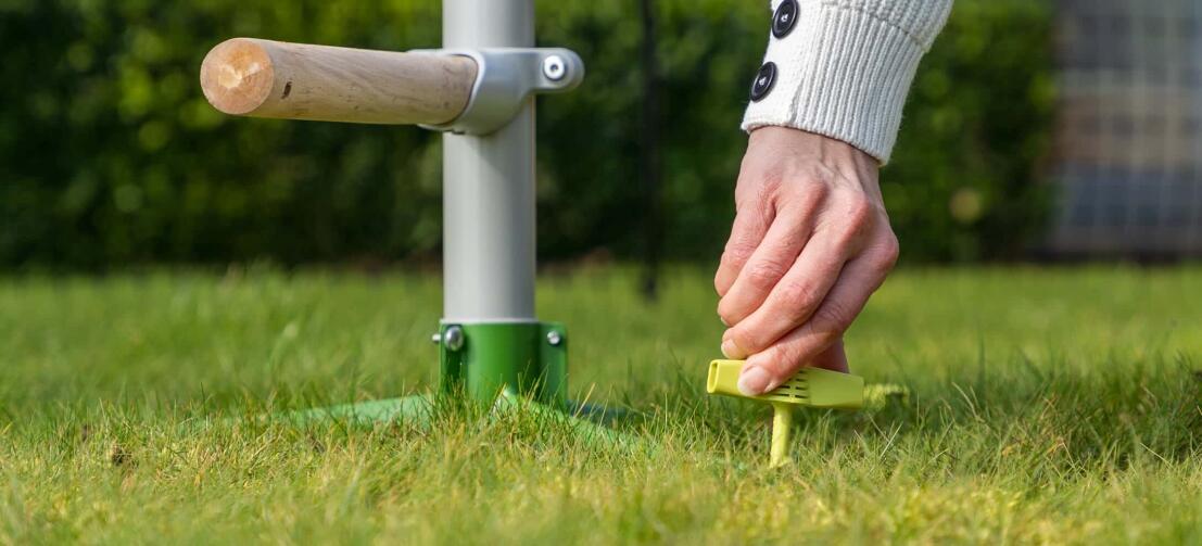 woman securing the freestanding universal chicken perch system to the land using the omlet screw pegs