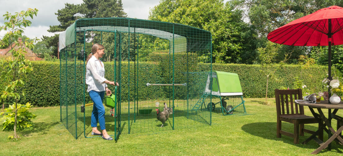 Lady going into Omlet Chicken Walk in Run in garden