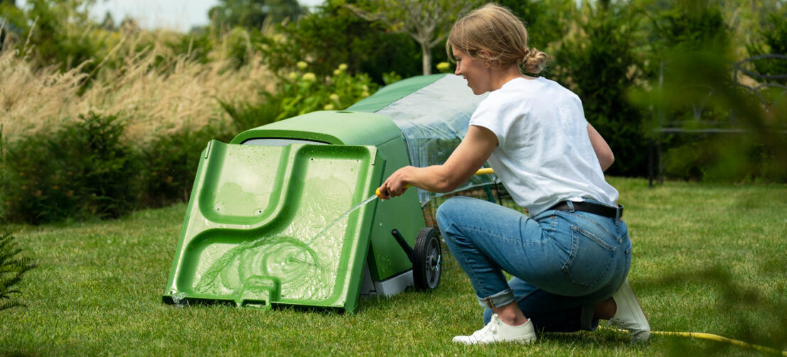 Woman cleaning the Eglu Go Hutch with a hose