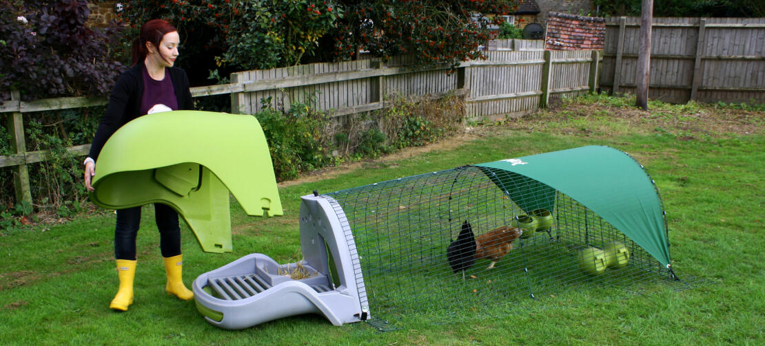 A woman removing the lid of an Eglu Classic chicken coop