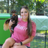 Woman holding chicken in front of a Eglu Cube