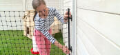 A woman connecting Omlet Chicken Fencing to a wooden wall.