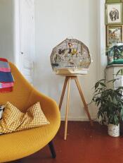 The cream Geo bird cage and stand set up in a living room.