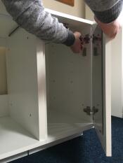 someone attaching a wardrobe door to a fido wardrobe with a mirror on it