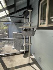 A grey cat napping in the grey hammock attached to the outdoor freestyle cat tree.