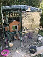 a walk in run with a wooden chicken coop inside with an autodoor