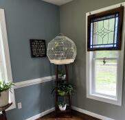 A white bird cage installed in the corner of a room