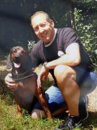 A man posing with a Bavarian Mountain Hound Dog.