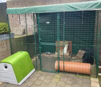 A rabbit in the  Outdoor Rabbit Run attached to the green Eglu Go Rabbit Hutch.