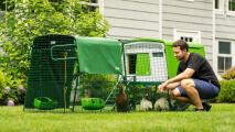 man crouching down next to an eglu cube large chicken coop