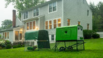 Eglu Cube chicken coop and run in a garden in front of a large house