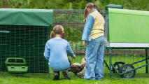 two little girls watching their chickens in the eglu go up chicken coop run