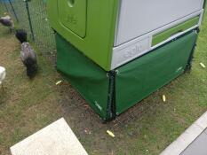 green covers around the bottom of a green eglu cube chicken coop