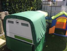 a large eglu cube chicken coop with an all weather cover over the top of it