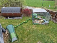 The outdoor rabbit run attached to the eglu go rabbit hutch in a garden,