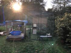 a large outdoor walk in run with a wooden chicken coop inside