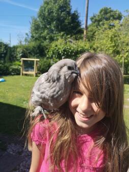 girl with a chicken perched on her shoulder in a garden