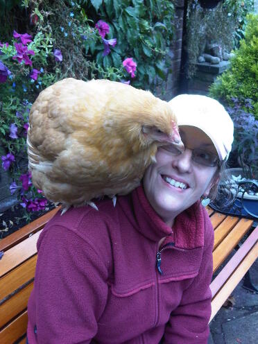 Lady sitting on bench with Chicken sitting on her shoulder