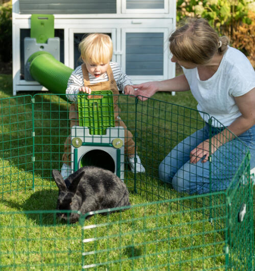 Girl and woman looking at a rabbit in a Zippi rabbit run
