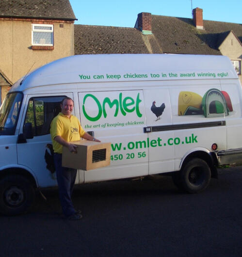 A delivery driver next to an Omlet branded van carrying a box of chickens