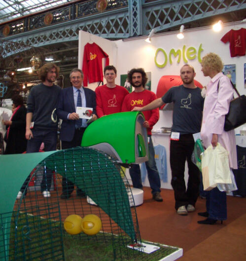 A group of people posing at a stand with the eglu cube chicken coop