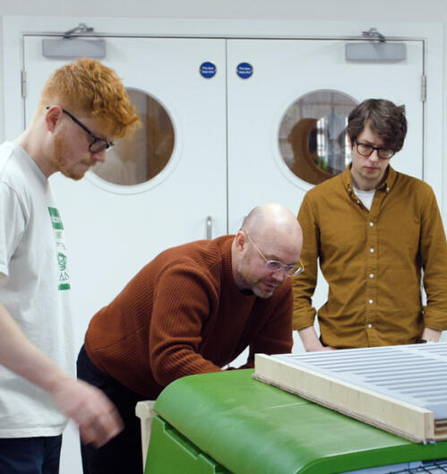Four men examining the eglu cube chicken coop in a workshop