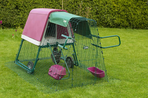 A raised eglu go chicken coop with an extension and cover in a garden