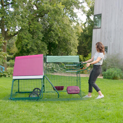 A woman moving a chicken coop using the handles.