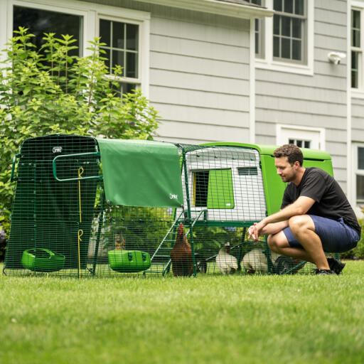 man crouching down next to an eglu cube large chicken coop