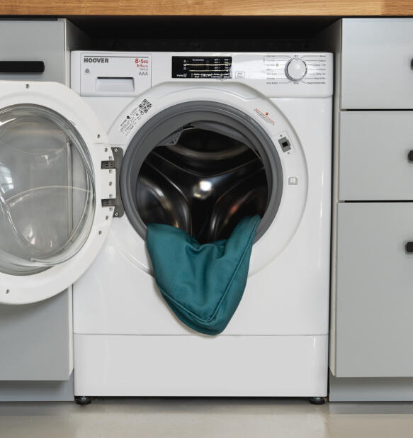 Washing machine with door open and Bolster bed cover in Shaded Spruce print inside.