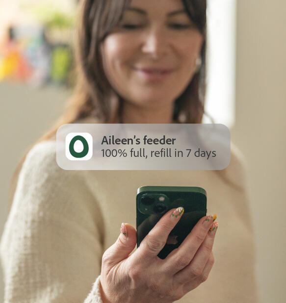 lady receiving a phone notification from her smart chicken feeder
