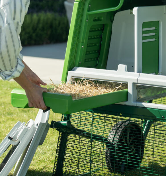 woman removing the Eglu Pro chicken coop nest box tray for easy cleaning