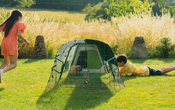 Two children playing around an Eglu Go Hutch.