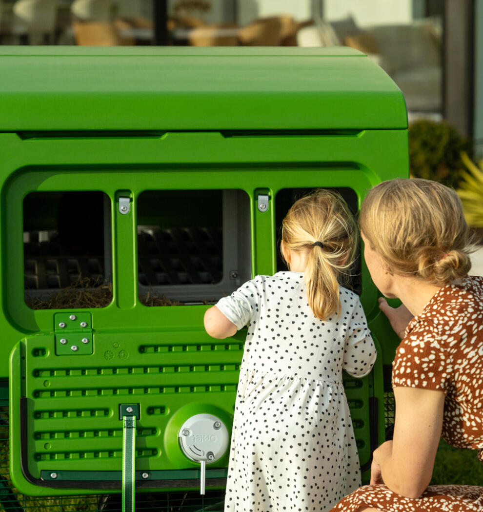 Mother and daughter looking into the triple egg port of the large Eglu pro chicken coop