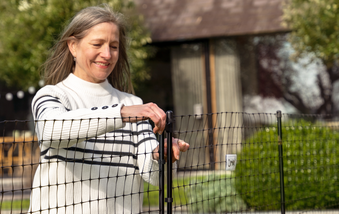 Woman closing the gate of Omlet's Chicken Fencing
