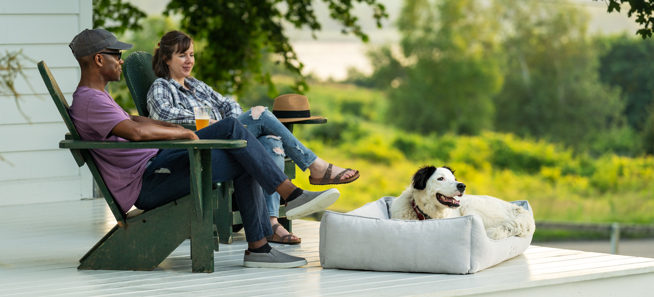 Dog sat on their Omlet Nest dog bed in Corduroy Pebble, enjoying spending time outside with their owners.