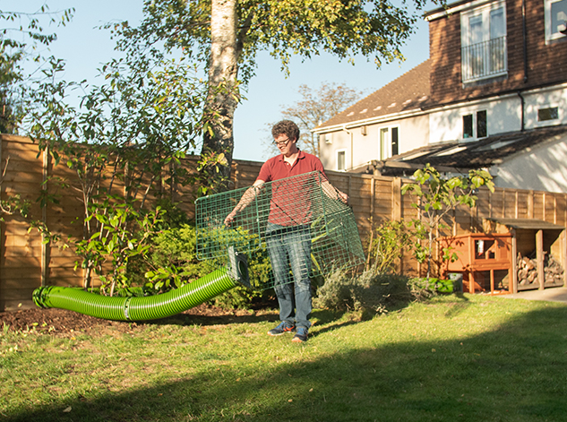 man moving easily the guinea pig run to another location in his garden thanks to the flexible tunnels connected to the hutch